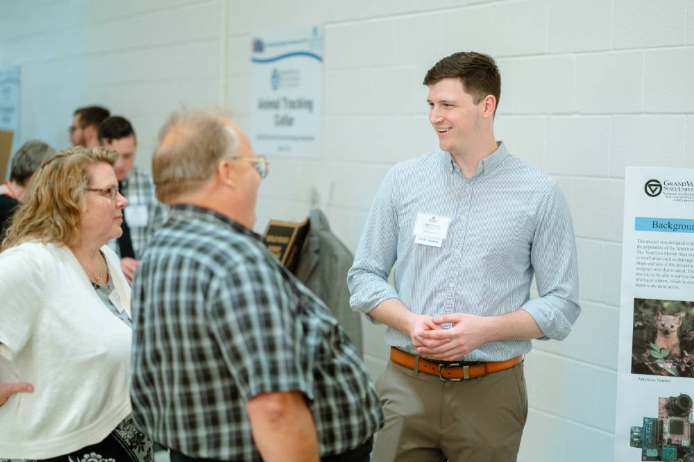 An engineering student speaking with guests at the Engineering Design Project Preview